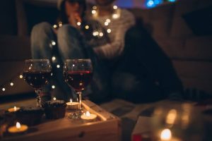 Soft-focus photo with wine in the foreground and a couple enjoying their custom wine storage in the background.